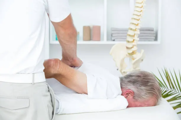 Hombre acostado recibiendo fisioterapia de un especialista, enfocándose en aliviar dolor lumbar y mejorar la columna con descompresión espinal no quirúrgica