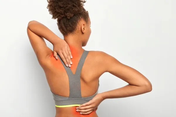 Mujer con dolor lumbar tocándose la espalda, atención de especialista en lesiones deportivas