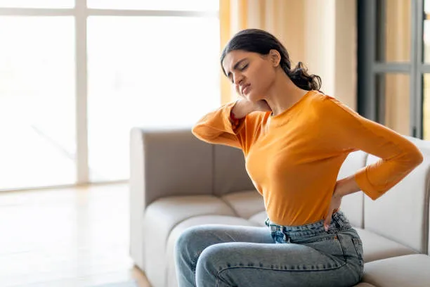 Persona que sufre de dolor lumbar, buscando soluciones para mejorar su postura y aliviar la incomodidad diaria