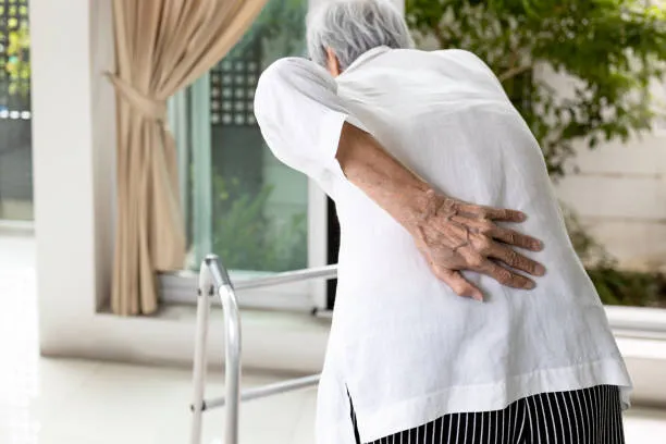 Mujer de edad adulta con dolor lumbar asociado a degeneracion discal, sosteniendo su espalda debido a molestias que limitan su movimiento y calidad de vida.