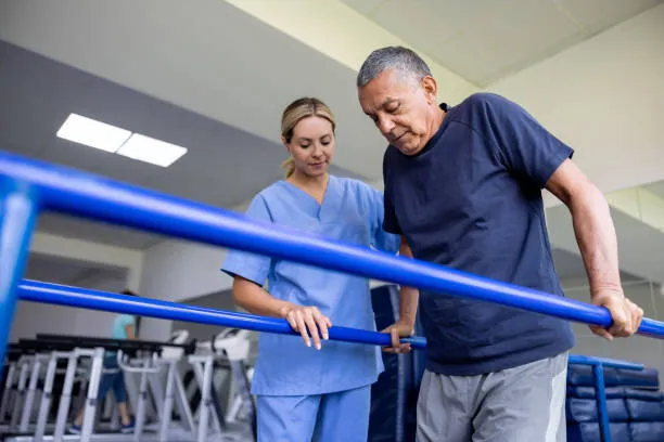 Hombre recibiendo apoyo terapéutico para recuperar movilidad tras lesiones columna, trabajando con ejercicios asistidos que buscan fortalecer su cuerpo y mejorar su capacidad para caminar sin dolor.
